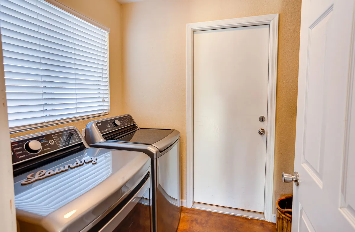 This image clearly shows a dedicated laundry area with a washing machine, dryer, and a door, highlighting the home's practical amenities for handling laundry during extended stays. The scene conveys a sense of organization and everyday convenience.
