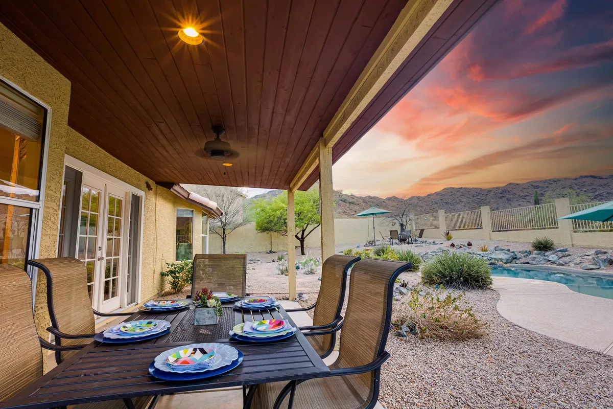A stylish outdoor dining setup featuring a table with decorative plates, set beside the pool with a beautiful mountain view in the background. The scene invites alfresco meals, relaxation, and enjoyment of the natural surroundings.