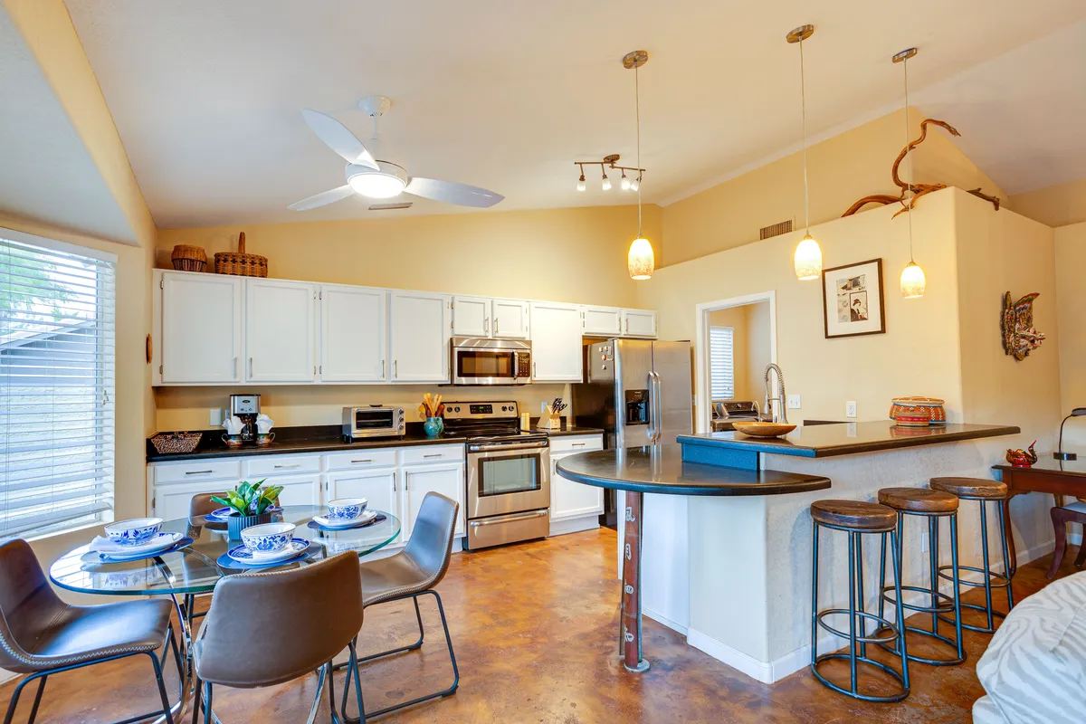 A welcoming great room scene with a kitchen island, a dining table, stainless steel appliances, and decorative wall art. The space is set up for cooking, dining, and socializing, exuding warmth, and is ideal for family dinners and gatherings.